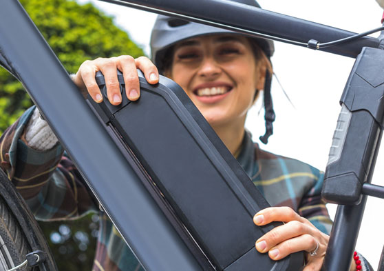 Chica colocando la batería en una bicicleta eléctrica