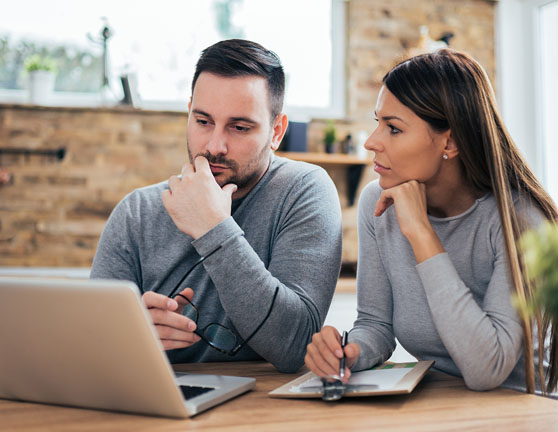Pareja joven pensativa mirando portátil